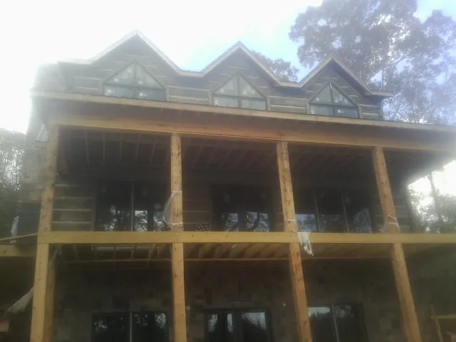 Dormers and porch framing on a large log home under construction — Roof Coating work by our crew in Harrison